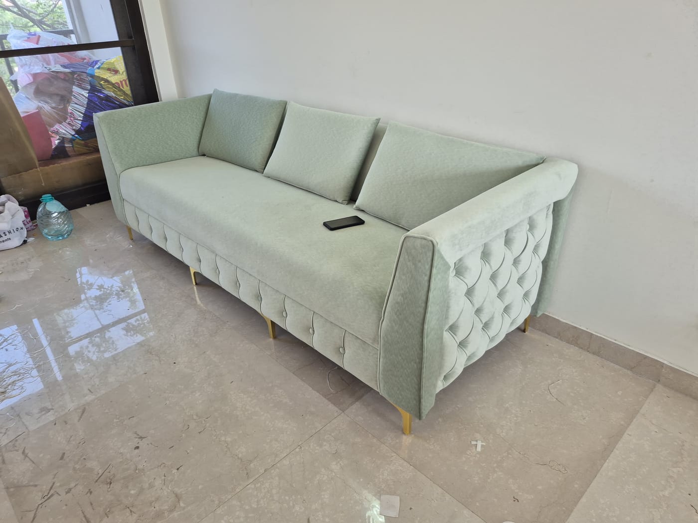 A reupholstered tufted sofa with brass legs